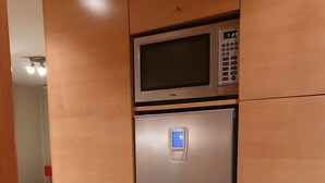 Una kitchenette moderna y compacta, con microondas integrado y refrigerador digital.
