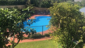 Une piscine entourée de verdure, offrant une vue sur des montagnes lointaines et un plan d’eau.