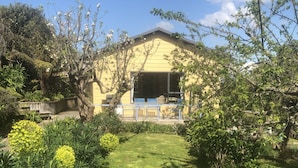 Un bâtiment jaune doté d’un patio couvert, entouré d’une végétation bien entretenue et d’une pelouse verdoyante.