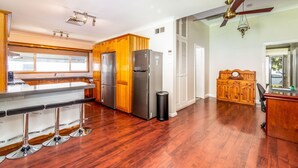 A spacious kitchen with wooden cabinets, stainless steel appliances, and a bar area with stools. - Very comfortable, spacious home. (Cessnock)
