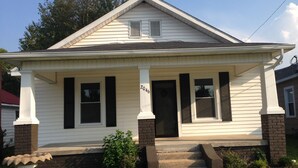 A single-story house with a front porch, a brick foundation, and a number '2046' on the door.