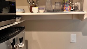 Une cuisine équipée d’une cuisinière, d’un four à micro-ondes et d’une étagère contenant divers ustensiles de cuisine.
