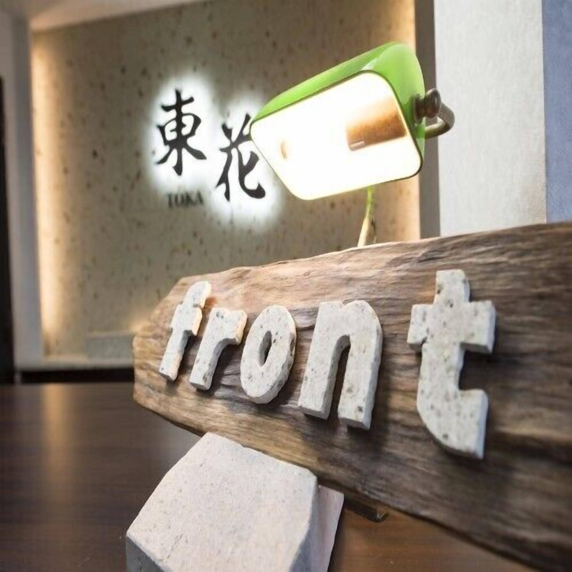 Un letrero de madera con la palabra 'front' y una lámpara verde encima.