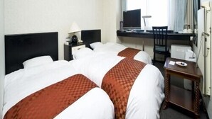 Ein Hotelzimmer mit zwei Betten, einem Schreibtisch, einem Stuhl, einem Fernseher und einer Klimaanlage.