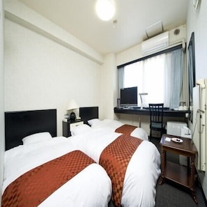 Hotellihuone, jossa on kaksi sänkyä, työpöytä, tuoli, televisio ja ilmastointilaite.