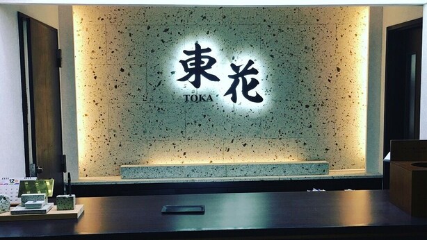 Ein Empfangsschalter mit einer Wandtafel, die 'TOKA' in japanischer Schrift zeigt.