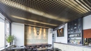 Ein Restaurantinneres mit Holzboden, Tischen, Stühlen, einer Wanduhr und einer Bar.
