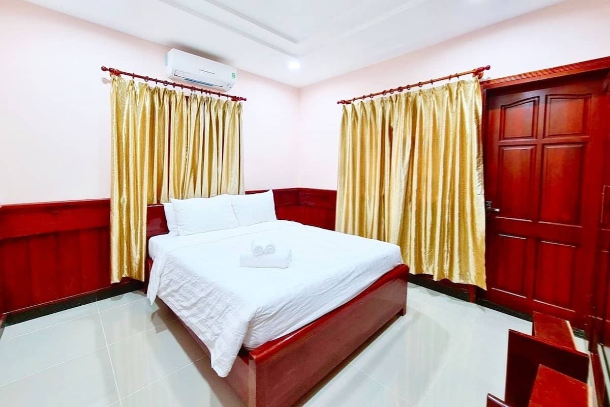 Een hotelkamer met een bed, gordijnen, een kledingkast en een airconditioner.