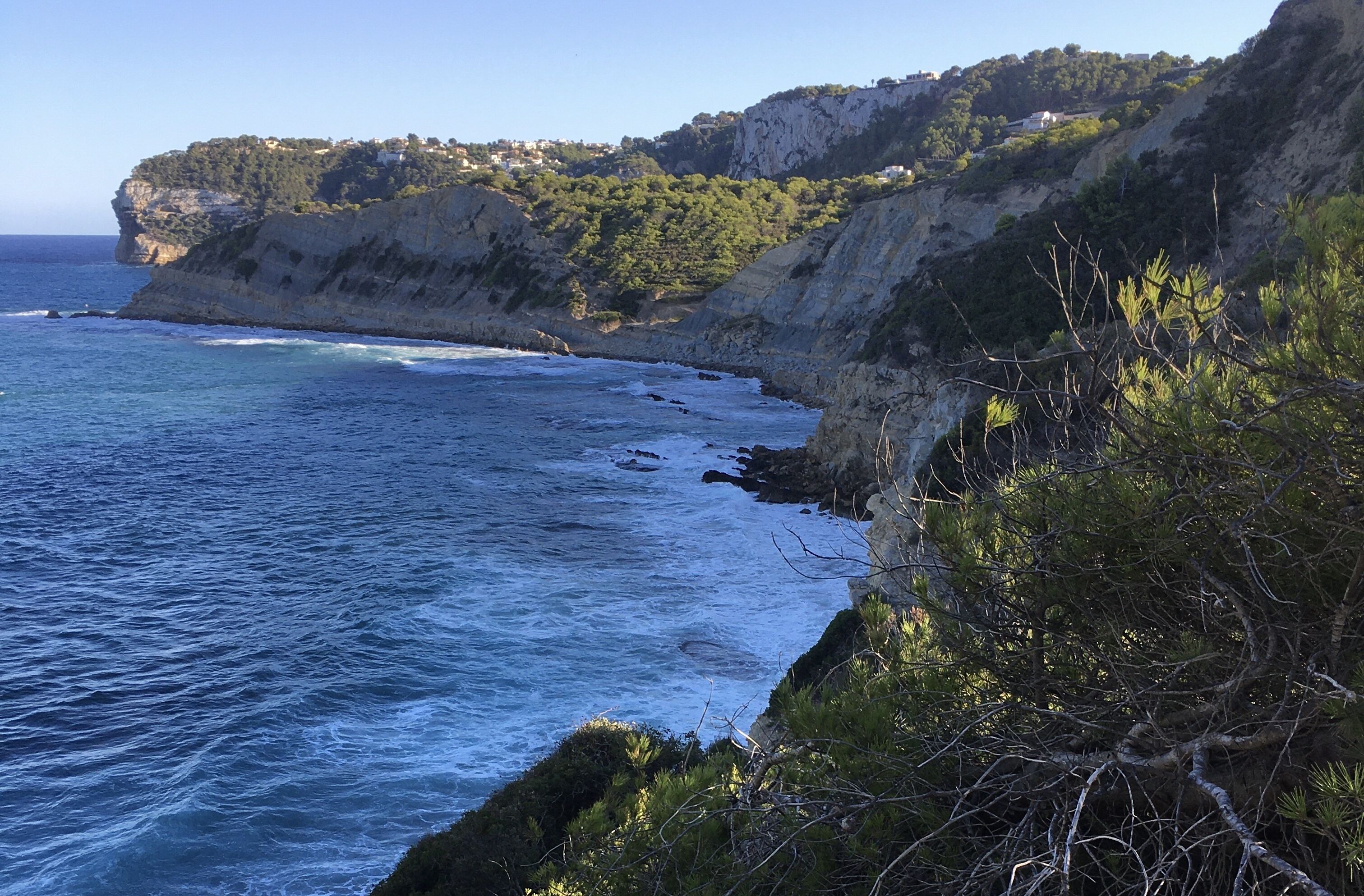 A coastal landscape with cliffs, a clear sky, and a view of the sea.
