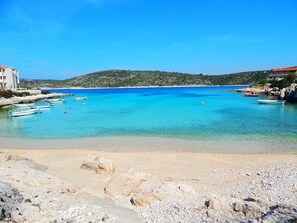 A coastal scene with clear turquoise waters, boats, and rocky terrain.