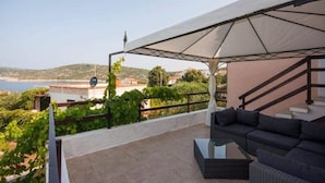 Une terrasse avec un canapé et une table, offrant une vue sur un paysage côtier.