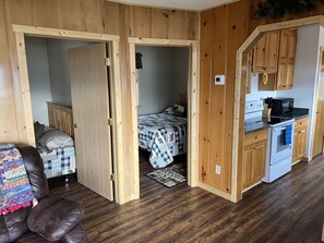 A compact room with a bed, a small kitchenette, and a brown leather chair. - Up North Retreat on Lake Waukenabo (Palisade)