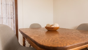 A wooden dining table with a bowl of decorative items on it, surrounded by chairs.