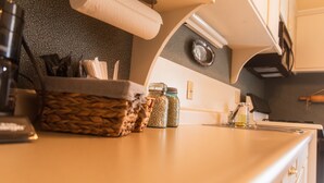 A kitchen with a wooden countertop, a basket, jars, and a paper towel dispenser.