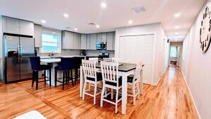 Una cocina moderna con una isla central, taburetes de bar y una mesa de comedor con sillas.