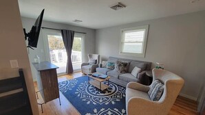 Una sala de estar con un sofá, sillones, una mesa de centro y un televisor.