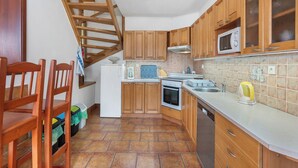 Une cuisine compacte avec des meubles en bois, un four encastré, un four à micro-ondes et un lave-vaisselle.