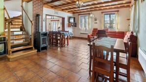 Un vaste espace de vie doté d’un plafond en bois, d’une table à manger et d’une cheminée.