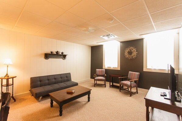 A living room with a sofa, two armchairs, a coffee table, a TV, and a fireplace.