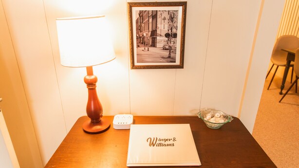 A hotel room with a wooden table, a framed black and white photo, a lamp, a small bowl, and a menu. - Sleeps 4 Fully Equipped Apartment Near Golf Courses (Corry)