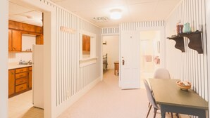 A narrow hallway with a kitchen on the left, a dining area with a table and chairs on the right, and a door leading to another room. - Sleeps 4 Fully Equipped Apartment Near Golf Courses (Corry)