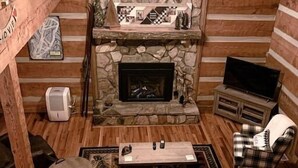 Ein gemütliches Blockhaus-Interieur mit Kamin aus Stein, Holzmöbeln und einem Fernseher.