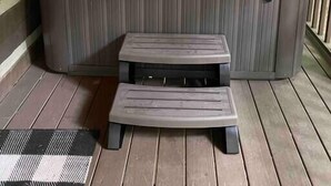 Ein Whirlpool auf einer Holzterrasse mit einer kleinen Bank davor.