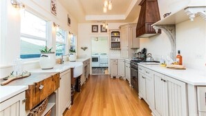 Une cuisine dotée de meubles en bois, d’un îlot central et donnant sur l’espace buanderie.