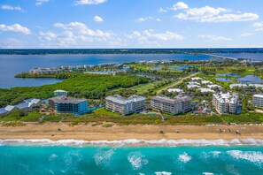 An aerial view of a coastal resort with beachfront properties, a marina, and a bridge in the distance. - Oceanfront 🌊 2 Bedroom End Condo on south Hutchinson Island in IRP 🌴 (Stuart)