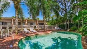 A pool area with lounge chairs, palm trees, and a building in the background. - Central Noosa location in Noosa Heads (Noosa Heads)