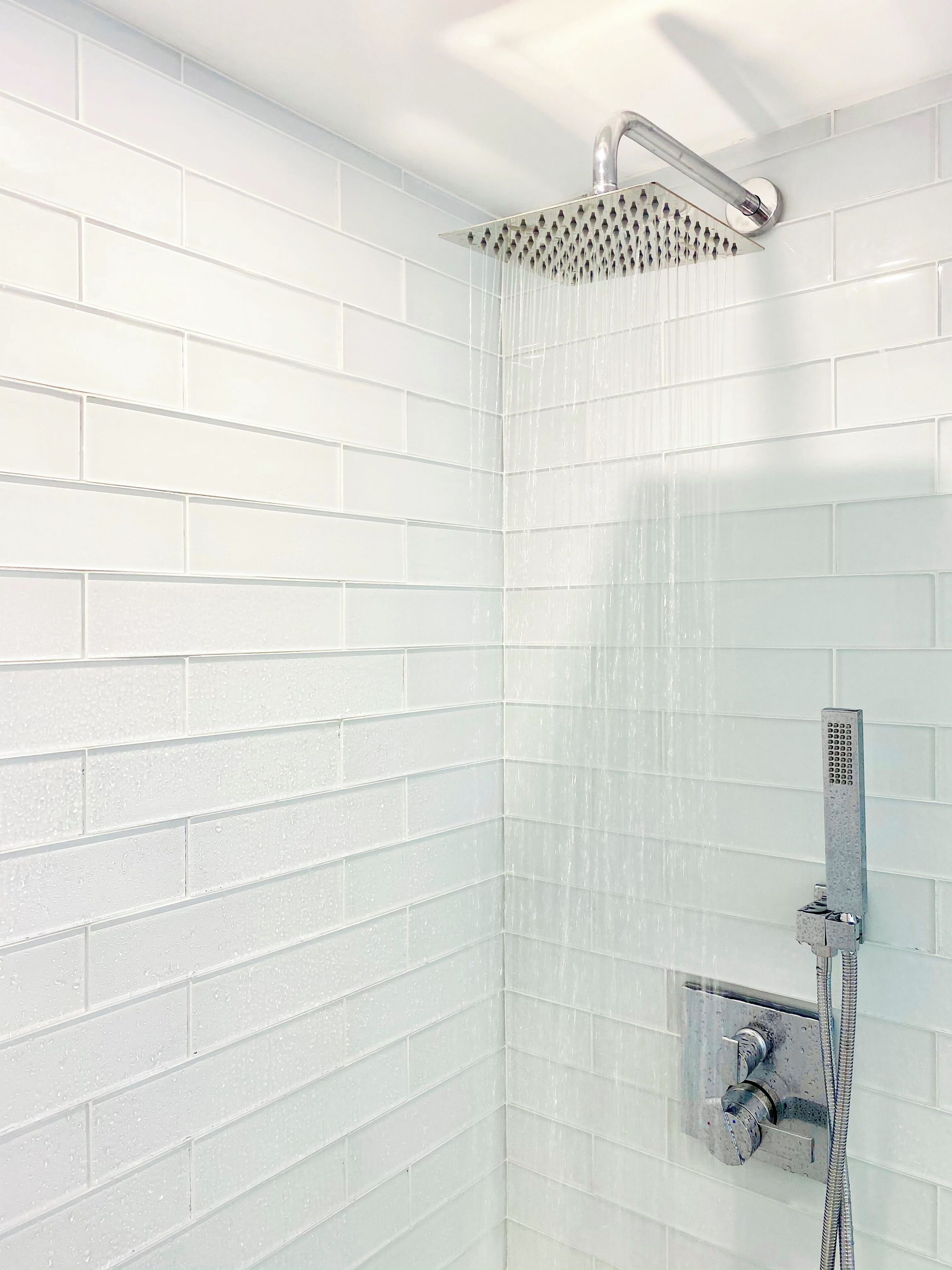 A shower with a rain-like water feature, a handheld showerhead, and a control panel.