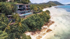 A beachfront property with a pool, multiple balconies, and lush greenery. - The View (Koh Samui)
