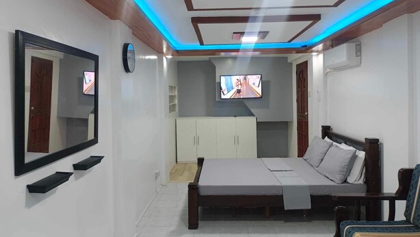 Un dormitorio con cama, televisor, armario y espejo.