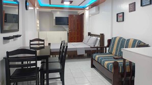 Un espacio habitable compacto con una mesa de comedor, sillas, un sofá, una cama y un televisor.