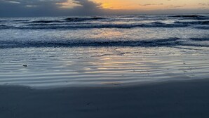 Ein Strand mit Wellen und einem Sonnenuntergang.