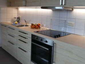 Una cocina moderna con horno integrado, armarios de acero inoxidable y un frutero sobre la encimera.
