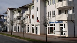 Een meerlaags gebouw met balkons, een apotheekbord en een heldere lucht.