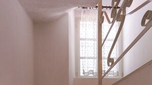 A wooden staircase with white walls and a window with lace curtains. - Apartment Ikana (Dubrovnik)