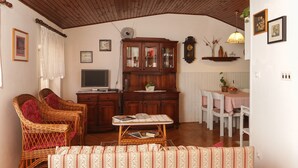 A cozy living room with wicker furniture, a wooden cabinet, and a dining table with chairs. - Apartment Ikana (Dubrovnik)