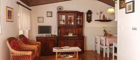 Un salón acogedor con mobiliario de mimbre, un aparador de madera y una mesa de comedor con sillas.