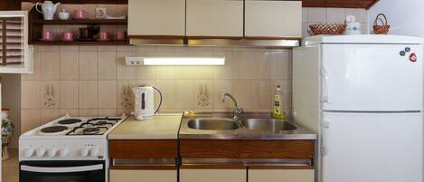 Cocina compacta con estufa, fregadero y refrigerador.