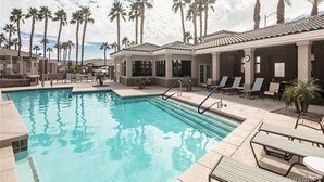 Una piscina con tumbonas y palmeras.