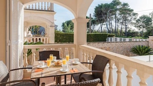 An outdoor dining area with a table set for breakfast, including croissants and orange juice. - Beach house for 6 persons, with pool and garden, in Playas de Muro, Mallorca (Muro)
