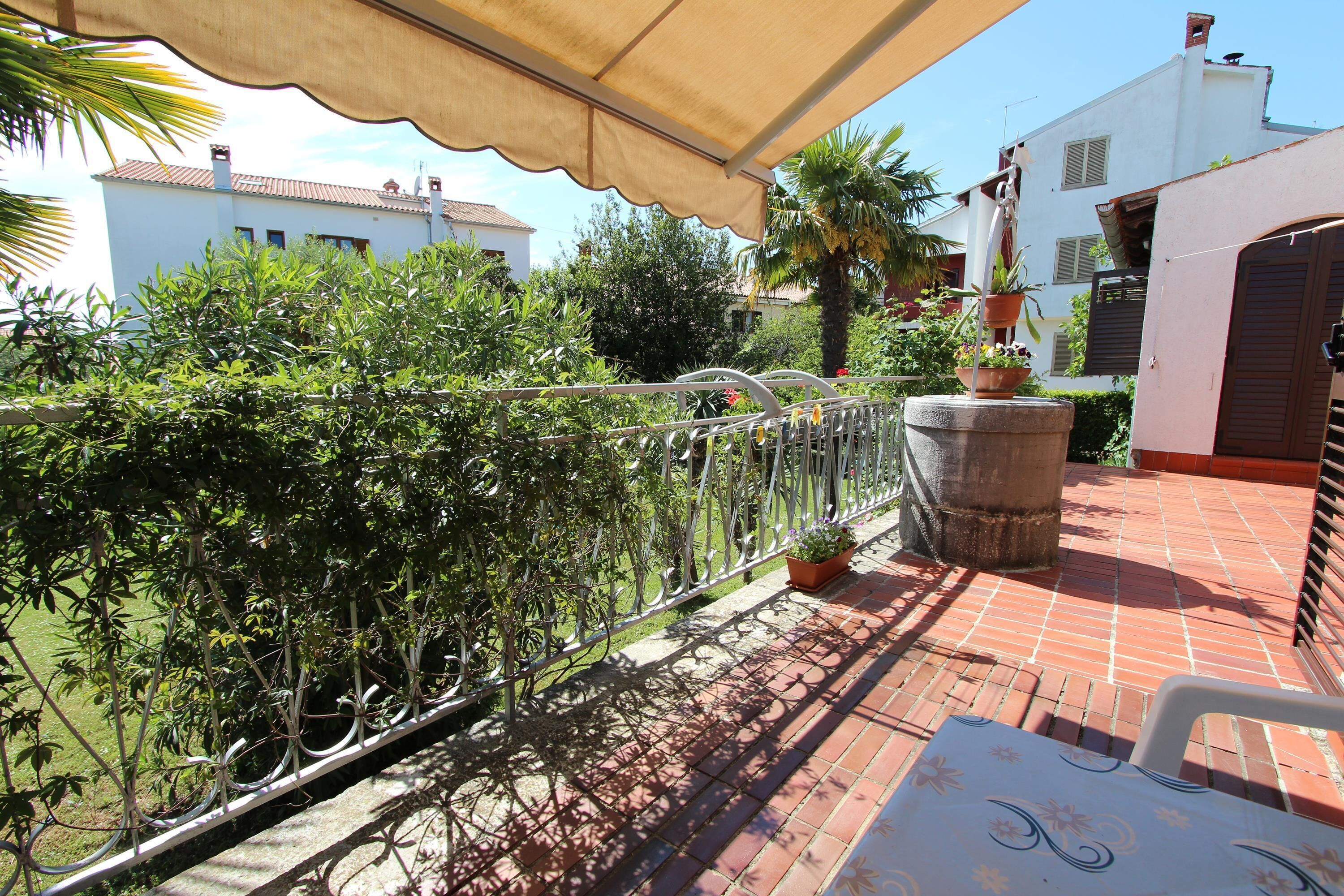 A balcony with a metal railing, potted plants, and a table.