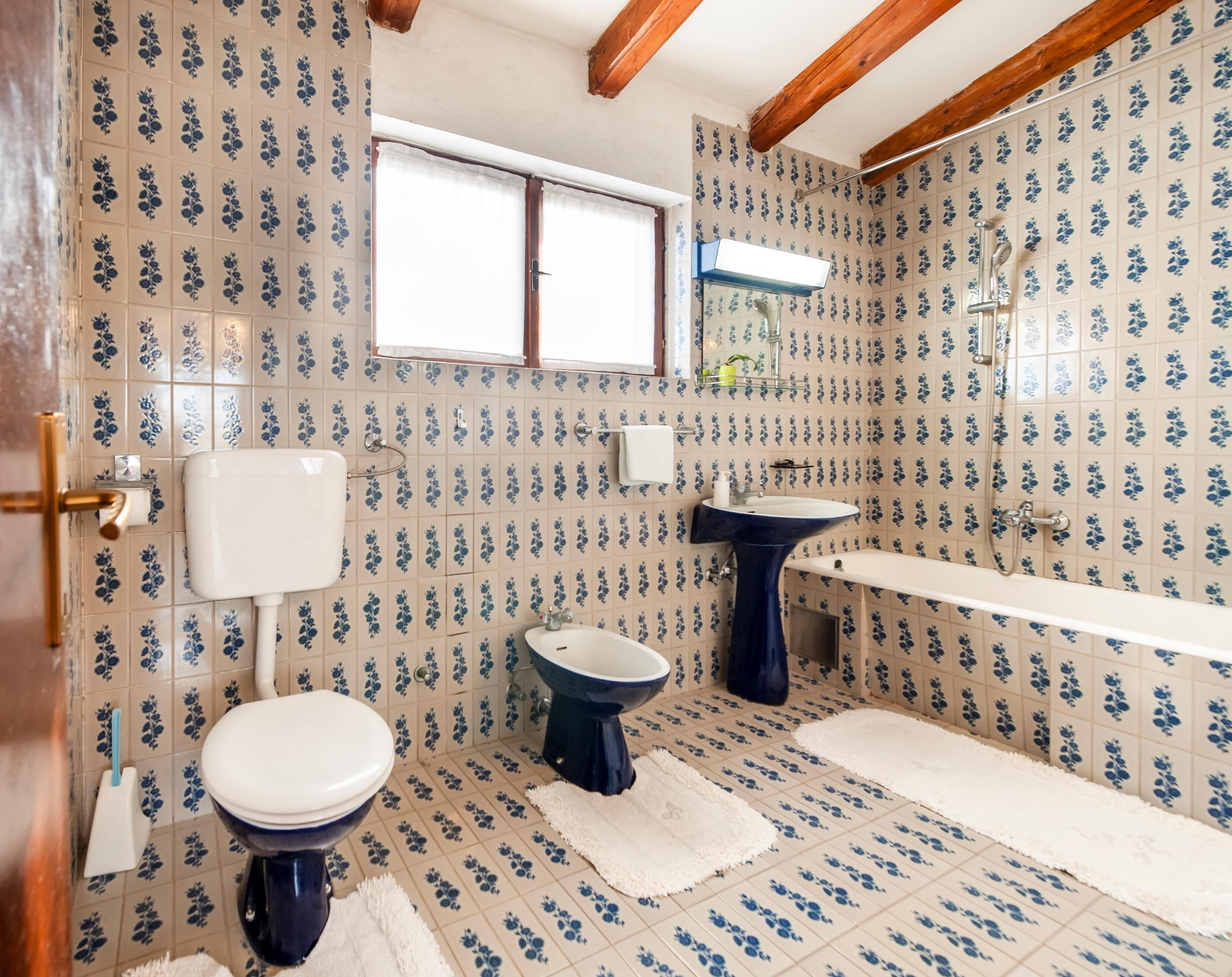 Un bany amb vàter, bidet i banyera, decorats amb motius florals als rajols.