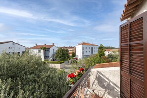 A residential area with white buildings, a tree, and a balcony with a metal railing. - Studio and Room Tea (Rovinj)