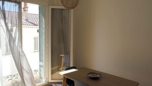 A room with a wooden table, a chair, a bowl, and a sliding glass door leading to an outdoor area with a tiled roof. - T3 rue Lamalgue-Mourillon Plages-Toulon (Toulon)