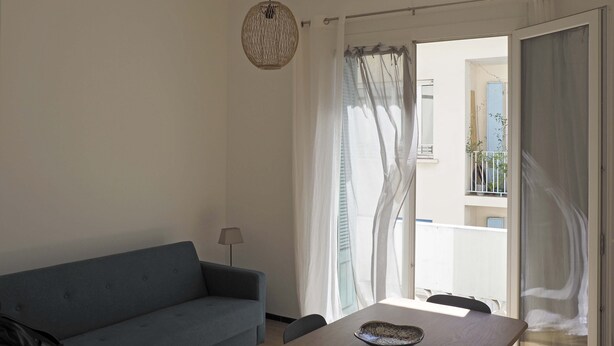 A living room with a sofa, a table, and a hanging light fixture. - T3 rue Lamalgue-Mourillon Plages-Toulon (Toulon)