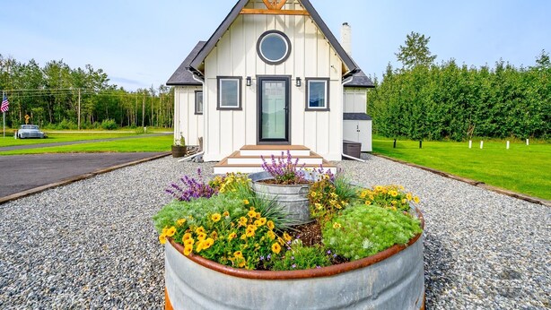 Una casa moderna amb un teulat triangular, una porta d'entrada i una finestra circular.