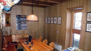 A wooden dining room with a table, chairs, a laptop, and a hanging lamp. - Chalet in Carezza al Lago (Carezza Al Lago)